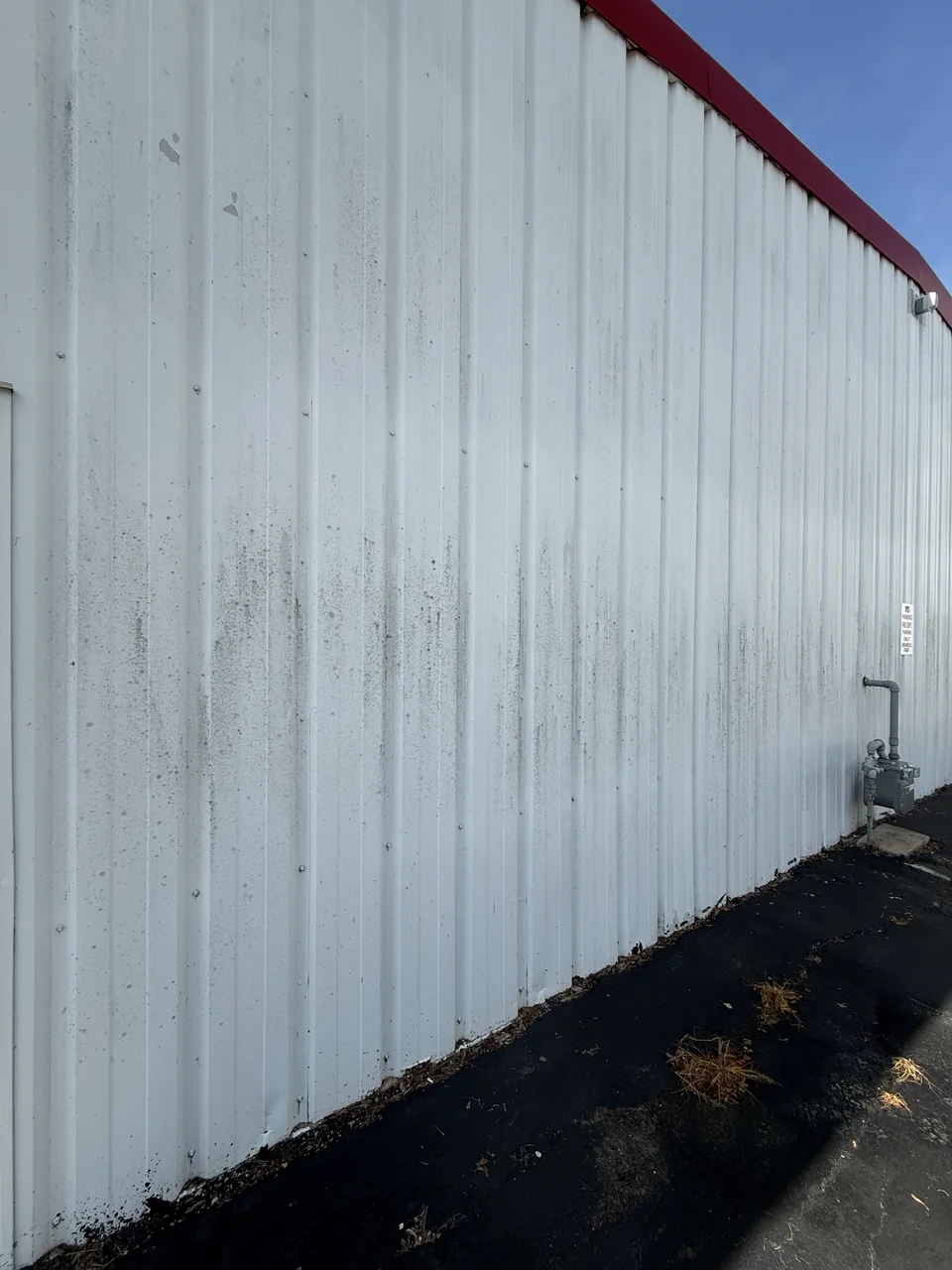 Metal siding on a commercial building before cleaning by River City Pressure Washing