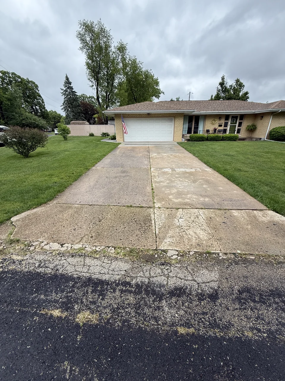 Concrete driveway leading to a garage before cleaning by River City Pressure Washing