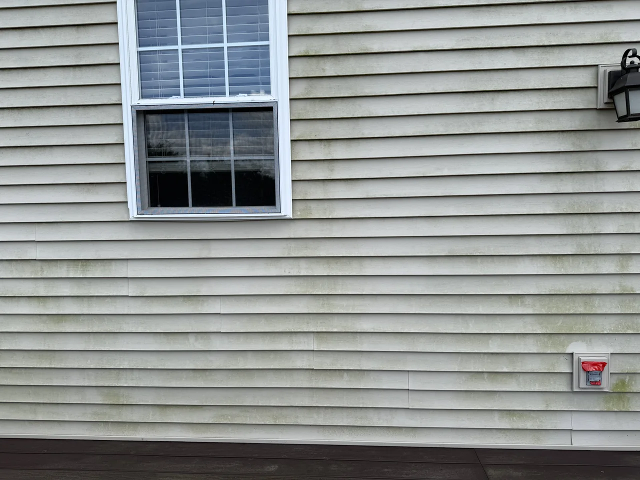 Vinyl siding around a window before cleaning by River City Pressure Washing
