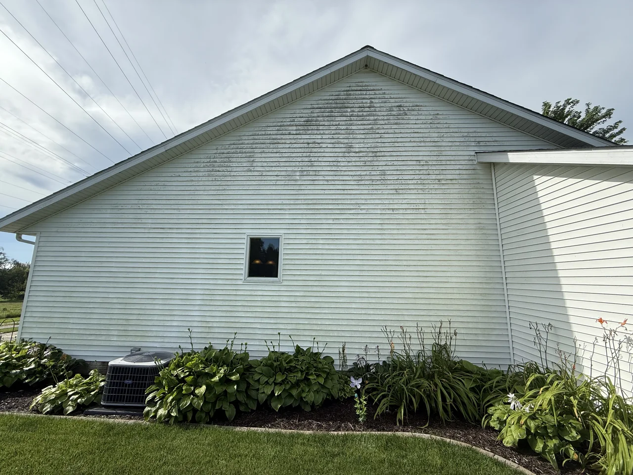 White siding on the side of a home before cleaning by River City Pressure Washing