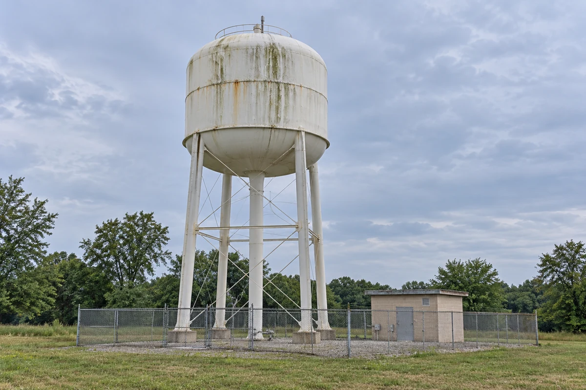 Exterior staining on an elevated water tower at a fenced utility site